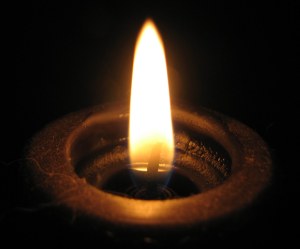 A close up image of a black candle with a lit flame