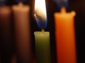 Close up of a green candle with a lit flame