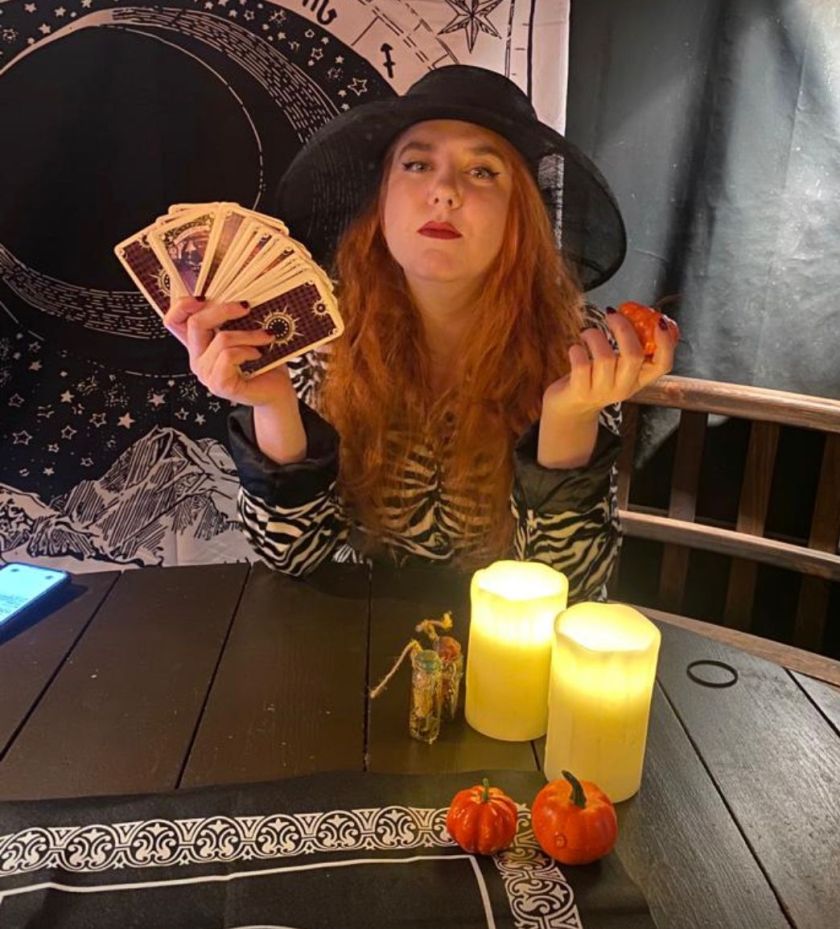 Digital Coven Founder Emma Carney looking Witchy holding tarot cards and wearing a black witchy hat